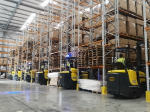 HSL Chairs - 5 forklifts turning down aisles between racked storage