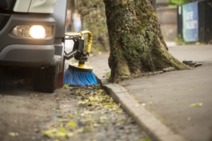 EMC Summer Street Sweeping - close up of street sweeper sweeping leaves along edge of road