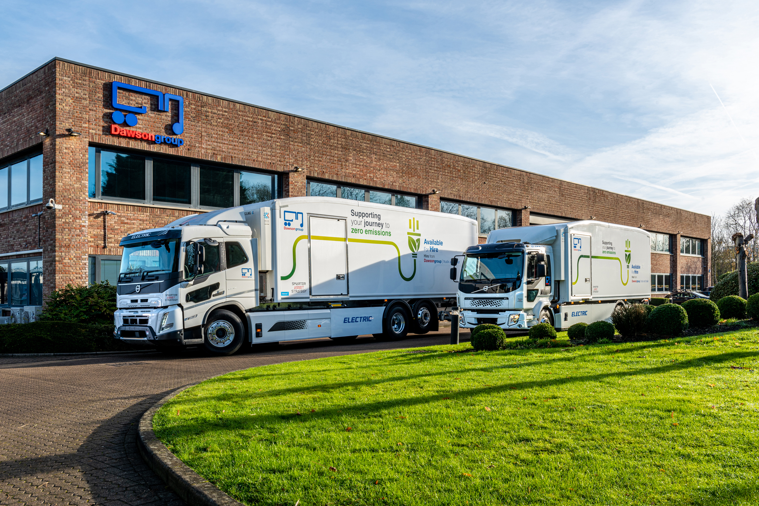 2 electric powered trucks in front of the Dawsongroup head office on a sunny day